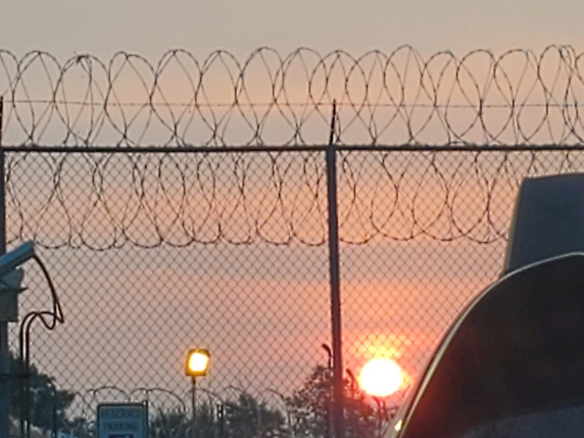Sunrise behind a barbed wire fence
