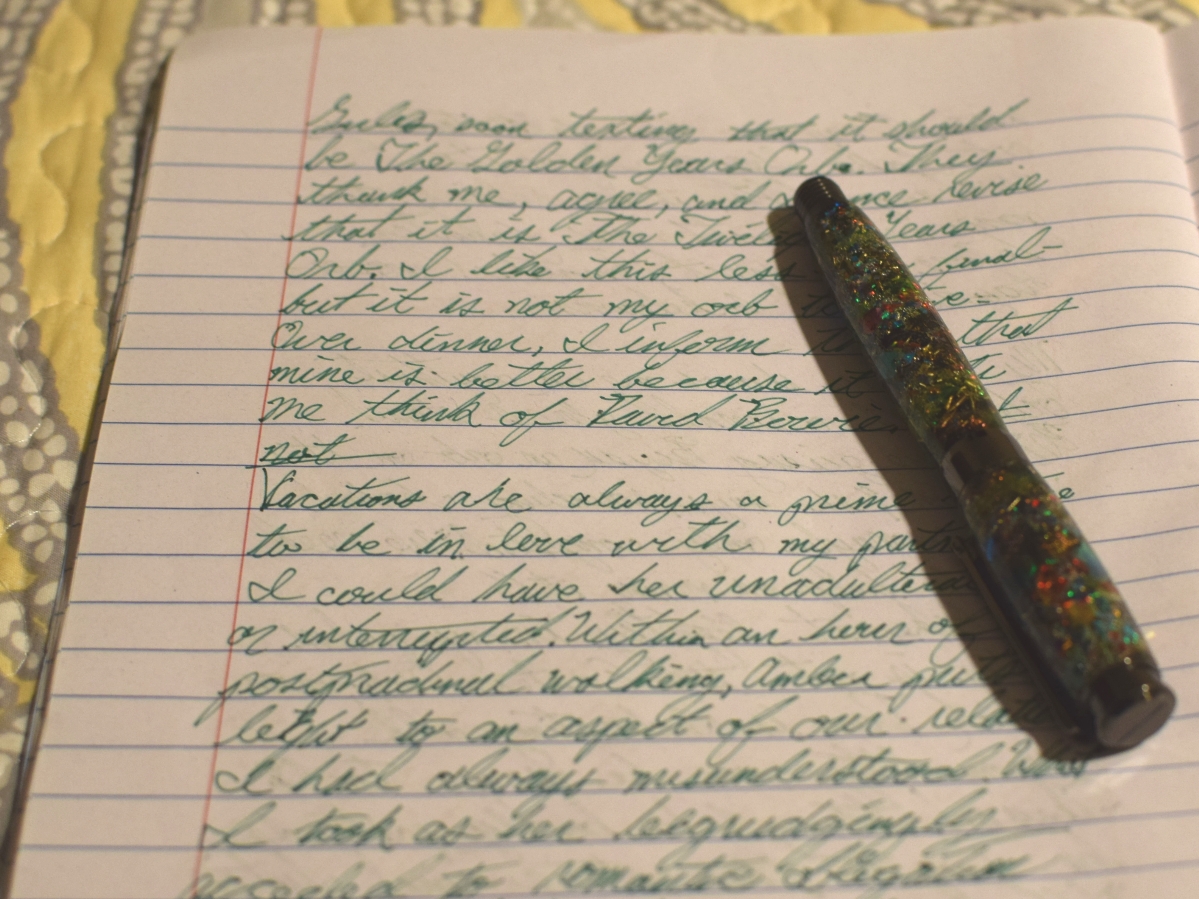 A fountain pen on a notebook with green script