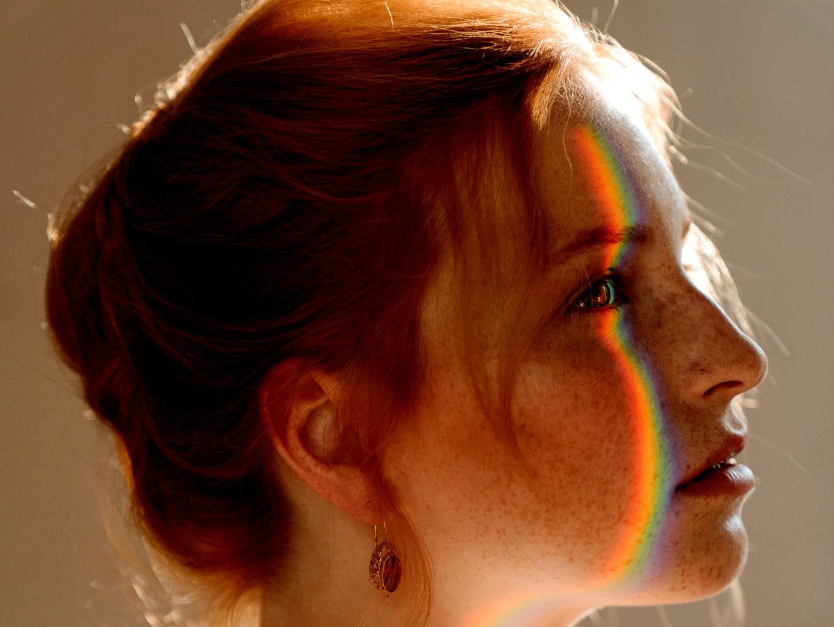 A redhaired woman with a rainbow on her face