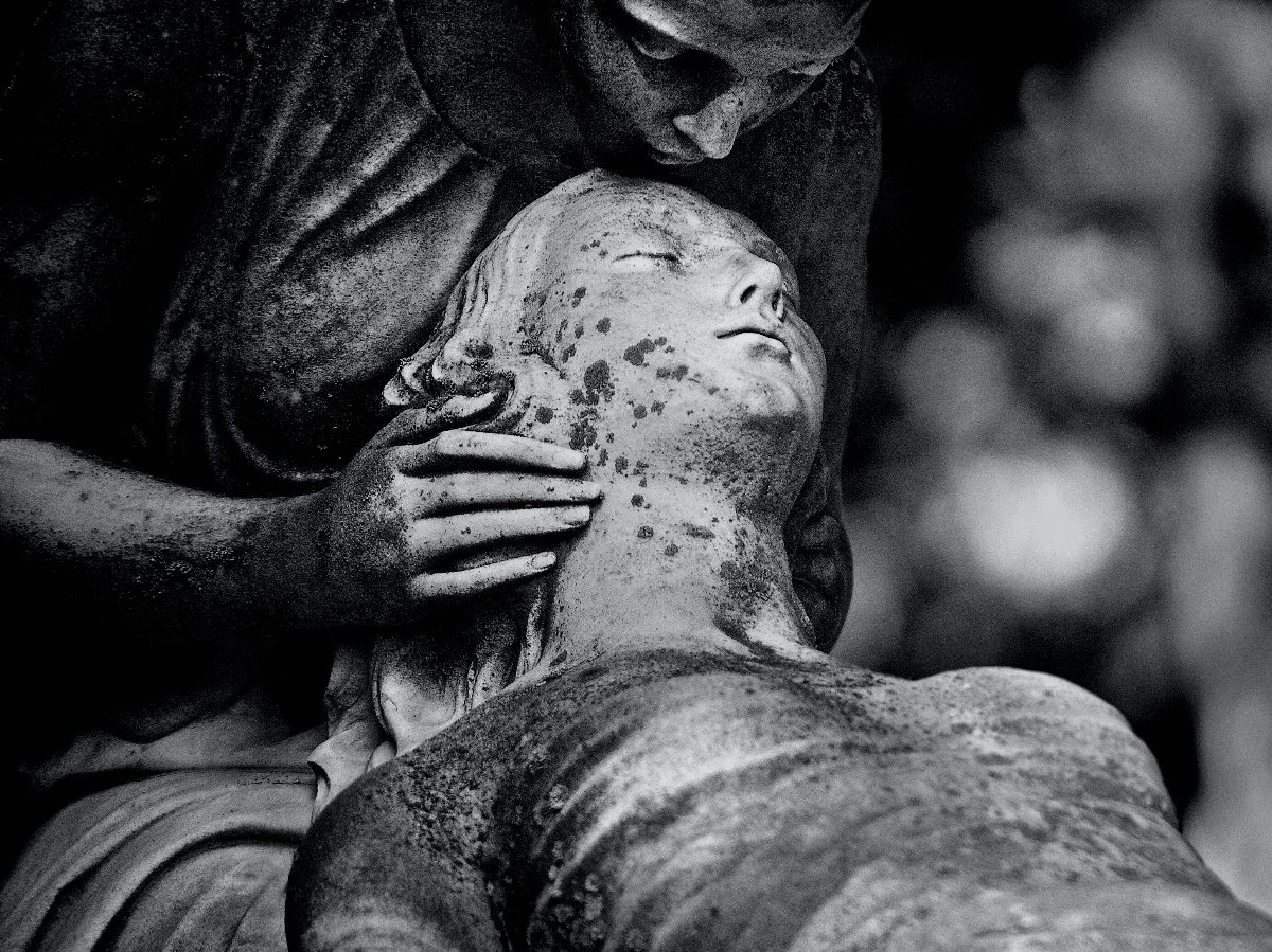 A statue of a person kissing the head of  dying woman