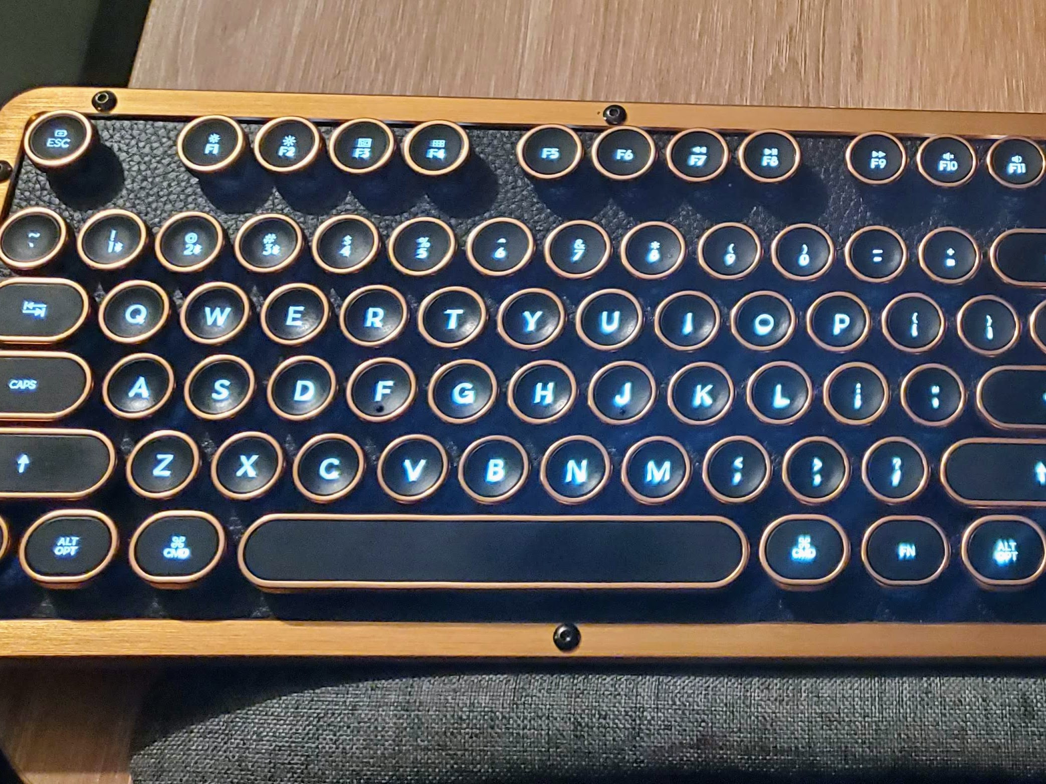 A keyboard with glowing keys, brass edging, and a leather back