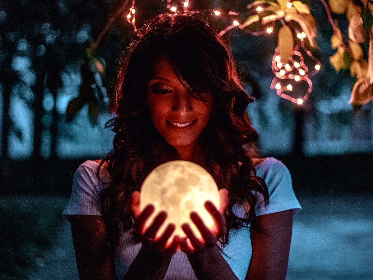 A woman smiling down at a glowing moon
