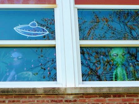 Two alien balloons behind a window