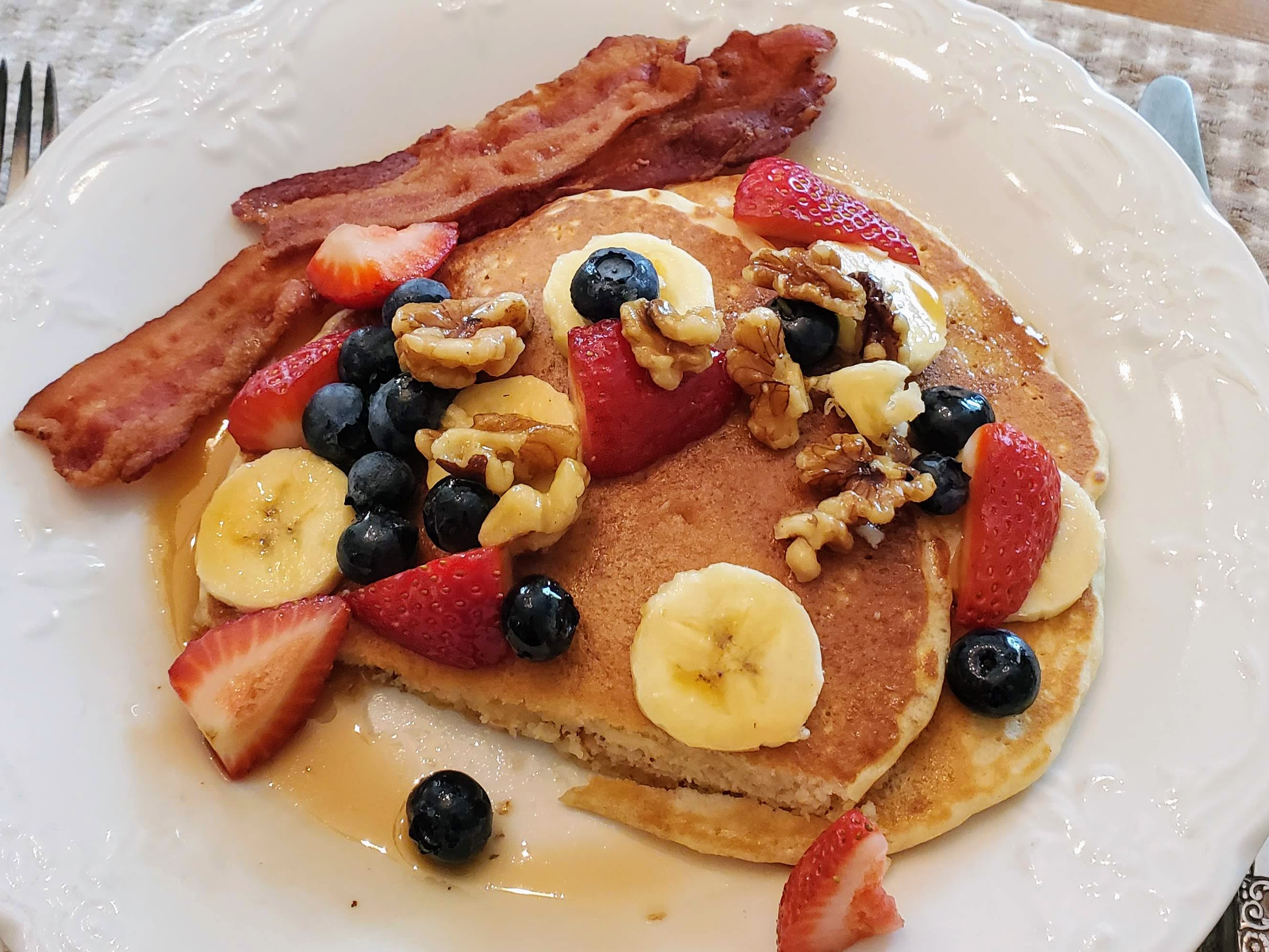 Pancakes covered in syrup, berries, and walnuts